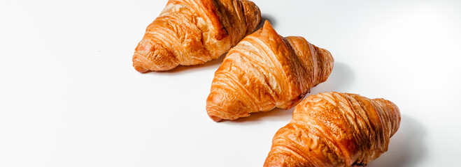 Banner with three large crispy croissants on a white background. A creative baking concept with space for text. Crispy soft pastries and breakfast bread