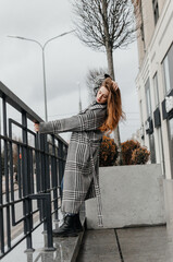 a girl in a gray coat and jeans holds on to the handrail