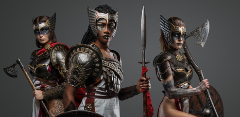 Shot of three ancient female warriors dressed in armors and armed axes and spear.