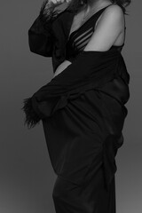 A pregnant woman in a black suit on a gray background. A pregnant woman. Studio pregnancy photo...
