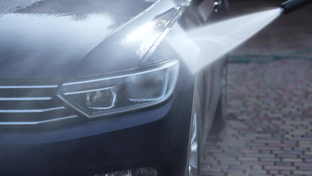 Washing a blue car with high pressure water cleaner, outdoors, close up