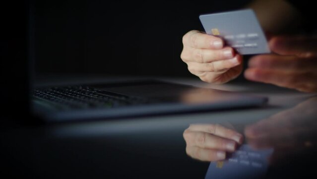 Lateral Dolly Close up of Young Woman Hand typing Credit Card Pin to Pay Online on Computer Laptop, Dark Room. Online Purchase Ecommerce Website Payments Concept. Blurred data.