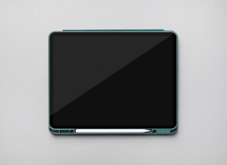 Modern tablet with stylus on gray paper background. Template for your design. Flat lay.