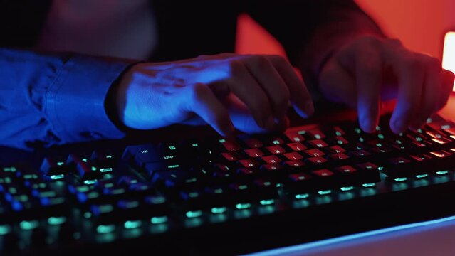 Freelance work. Computer programming. Unrecognizable male hands seamless loop chatting online on keyboard messaging playing game at dark neon color light.