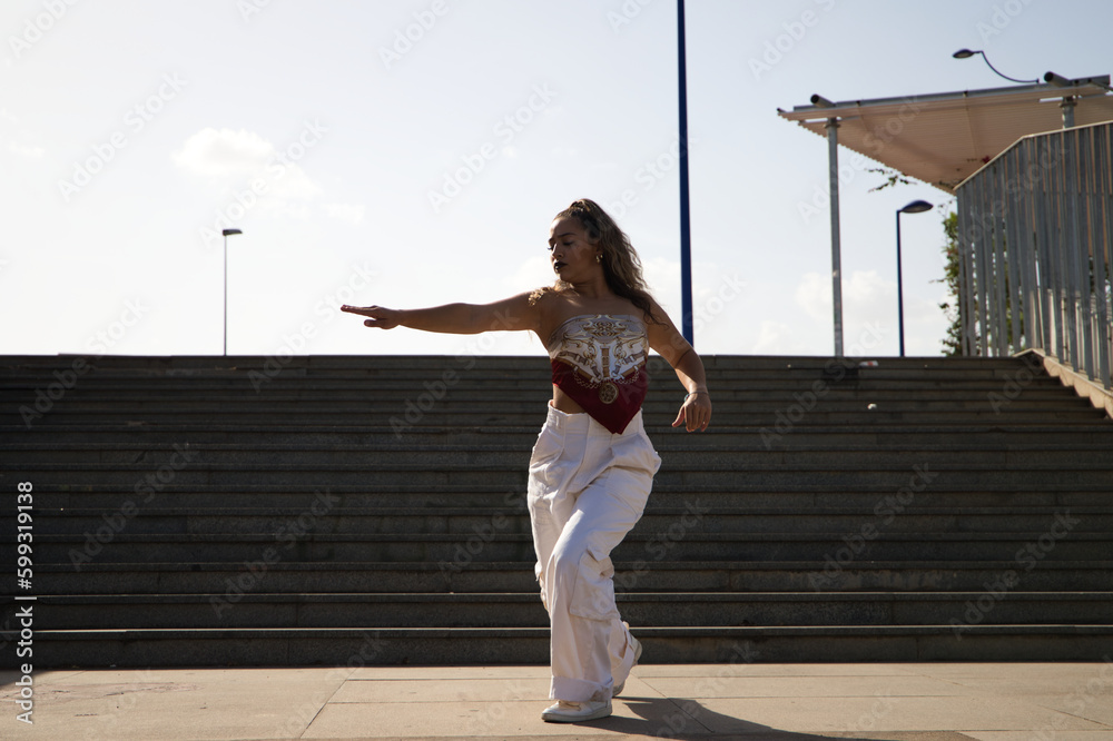 Wall mural Latin woman, young and beautiful dancing modern dance in the street and makes different expressions and postures. Concept dance, hip hop, dance, art, action, beauty, youth art.