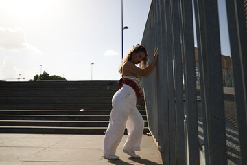 Young latin woman leaning on steel fence. The woman is a dancer of modern dance. Concept youth and social problems.