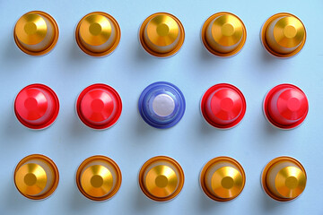 Multi-coloured coffee pods in a grid against a plain background. Top down view.