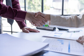 Businessman and businesswoman shaking hands above desk workplace office celebration partnership and successful business deal handshake concept	