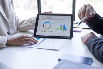 Team of confident business people point to graphs and charts to analyze market data, balance sheet, account, net profit to plan new sales strategies to business increase production capacity.	