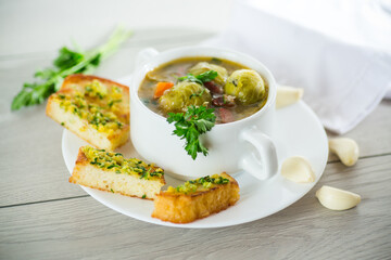 Hot cooked soup with Brussels sprouts, vegetables and croutons, in a plate.