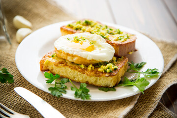 Fried croutons in batter with garlic and herbs and a fried egg in a plate.