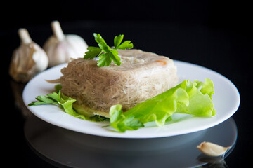 Boiled chicken meat aspic in meat gelatin broth in a plate