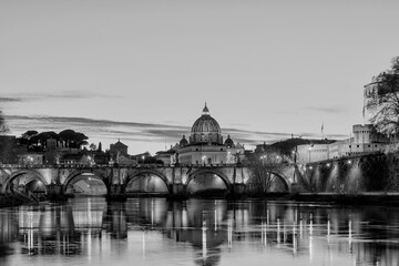 Black and white sunset of Rome, Italy, with the Ponte Sant'Angelo, the River Tiber with reflections on the water and St. Peter's Basilica in the Vatican