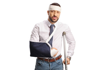 Young man with an arm sling and bandage on head leaning on a crutch
