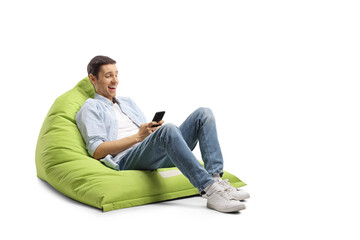 Young man seated on a bean bag laughing and looking at a smartphone