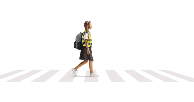 Female pupil with a safety vest crossing street at pedestrian crosswalk