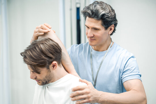 Male manual therapist helping his patient to work out the shoulder-joint