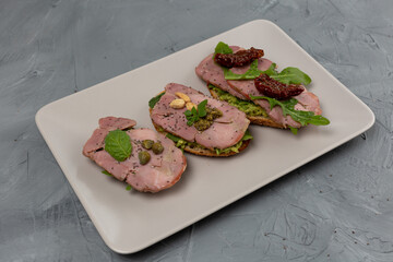 Assortment of three bruschetta with turkey meat, avocado, tomatoes, herbs, pesto, nuts, capers and chia seeds