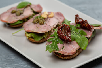 Assortment of three bruschetta with turkey meat, avocado, tomatoes, herbs, pesto, nuts, capers and chia seeds