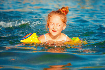 Fototapeta na wymiar Happy cute child girl swimming in the sea.