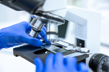 Unrecognizable scientist or doctor in medical gloves using microscope for research in laboratory