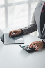 Businessman using a calculator to calculate numbers on a company's financial documents, she is analyzing historical financial data to plan how to grow the company. Financial concept.