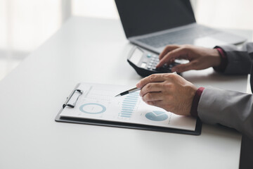 Businessman using a calculator to calculate numbers on a company's financial documents, she is analyzing historical financial data to plan how to grow the company. Financial concept.
