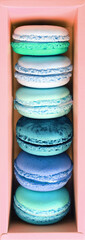 Top view of pastel blue and green macaron pastries in pink box