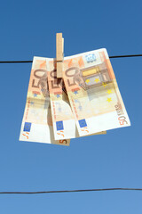 Money in the air. Concept of saving for purchase. Finances in the air. 50 euro banknotes hanging with a wooden clip from a wire with a blue sky background. 