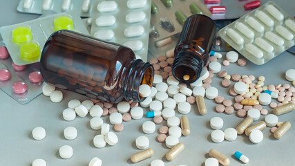 Medicine bottles and pills on gray background, selective focus.