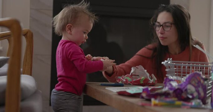 Mother makes christmas cards with toddler daughter in living room