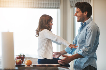 Fototapeta premium She loves to be hugged. a happy little girl reaching out to hug her father while sitting on the kitchen counter at home.