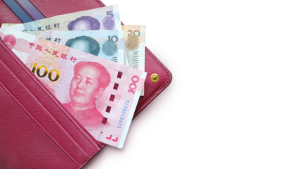 Chinese yuan bills in a leather wallet. Fucsia red wallet, purse. Wood background. Banknotes. Money in cash. Stack of notes. Fan of bills. 100 yuan (RMB)
