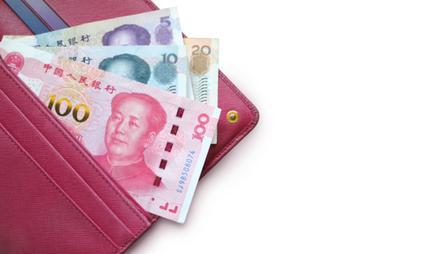 Chinese yuan bills in a leather wallet. Fucsia red wallet, purse. Wood background. Banknotes. Money in cash. Stack of notes. Fan of bills. 100 yuan (RMB)