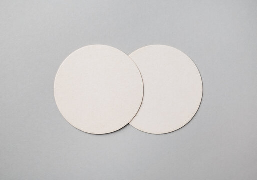 Two blank beer coasters on gray paper background. Responsive design mockup. Flat lay.