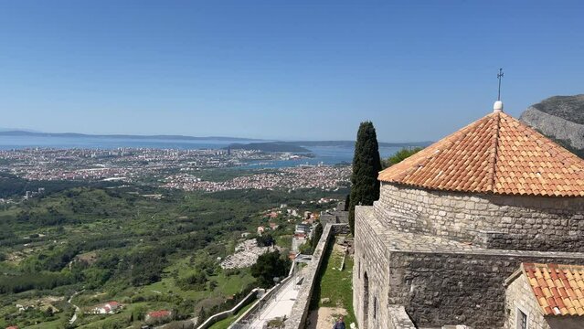 4K aerial video from Klis Fortress overlooking Split, Croatia, with sweeping views of the surrounding mountains, the Adriatic Sea, and the historic Dalmatian coastline. The medieval fortress provides 