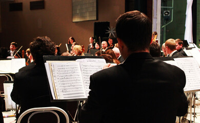 Symphony orchestra playing sheet music on stage