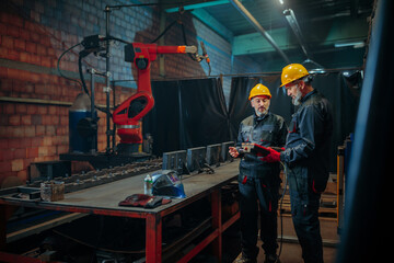 Obraz na płótnie Canvas Mechanical engineers with robotic welder.