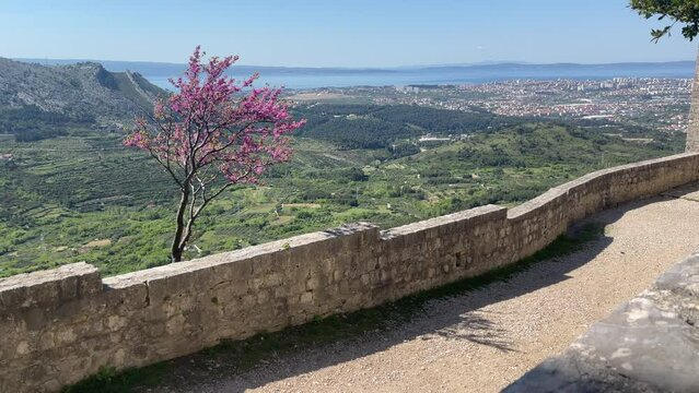 4K aerial video from Klis Fortress overlooking Split, Croatia, with sweeping views of the surrounding mountains, the Adriatic Sea, and the historic Dalmatian coastline. The medieval fortress provides 