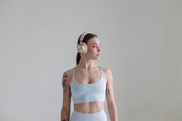 Young girl with brown hair, with a tattoo in a gray top and shorts on a white background with...