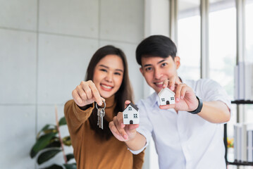 Blurred soft images, an Asian businessmen and woman holding home model and house keys, to business and real estate investing concept.