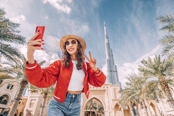 happy tourist asian girl taking selfie photos for her travel blog, in Dubai downtown  - obrazy, fototapety, plakaty