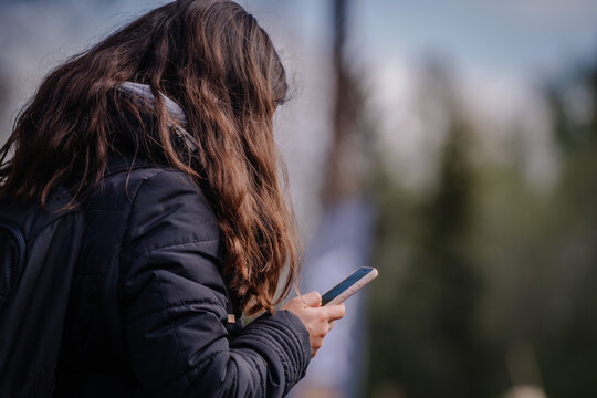 A woman standing on a sunny day and looking at her phone