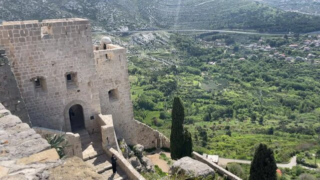 4K aerial video from Klis Fortress overlooking Split, Croatia, with sweeping views of the surrounding mountains, the Adriatic Sea, and the historic Dalmatian coastline. The medieval fortress provides 
