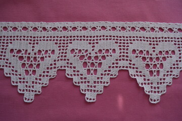 Pattern crocheted with white cotton yarn. Pink background.