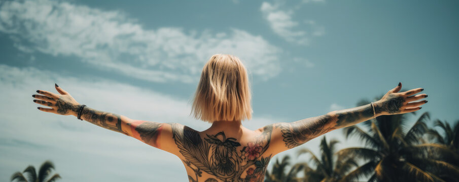 A young tattooed woman stands naked from behind, arms in the air as a sign of independence, facing a paradisiacal vacation landscape. Tattoo visible on the back of the woman. Generative AI