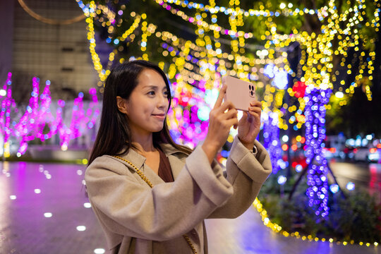Woman use smart phone to take photo with Christmas light decoration