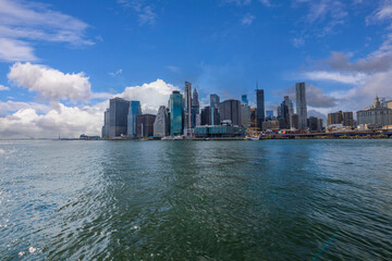 Naklejka premium Beautiful view of Manhattan skyscrapers against blue sky with white clouds. New York. USA. 