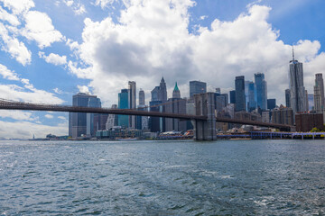 Fototapeta premium Gorgeous view of Manhattan skyscrapers and Brooklyn Bridge against blue sky with white clouds. New York. 
