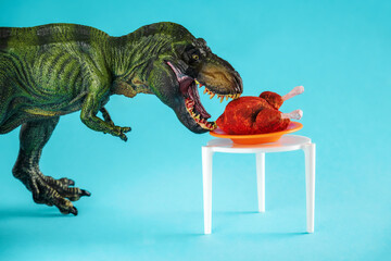 Dinosaur eats roast turkey on a blue background. - obrazy, fototapety, plakaty